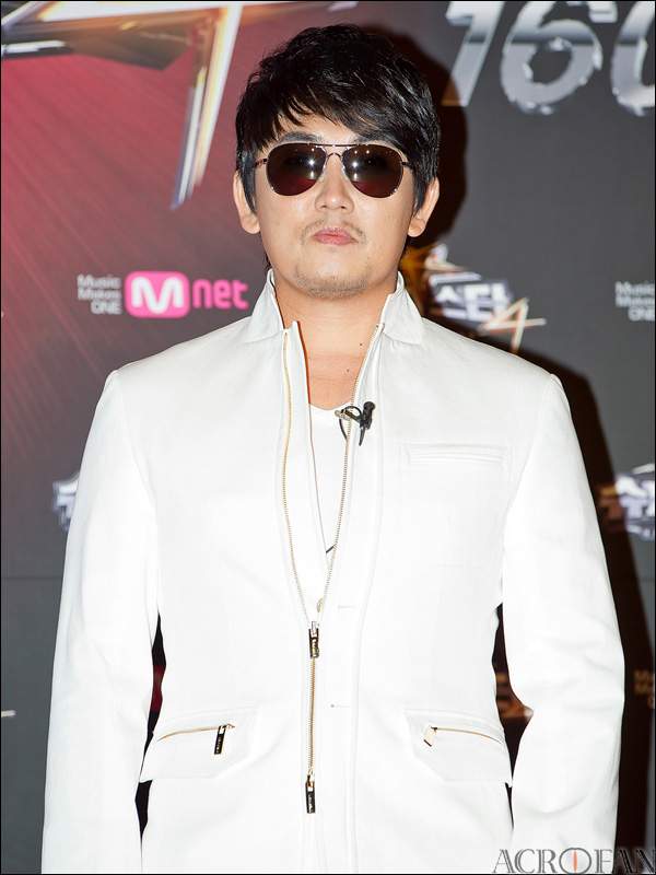 Potret Lee Seung-chul saat tampil bernyanyi di atas panggung konser musik dengan tata panggung megah di Seoul.